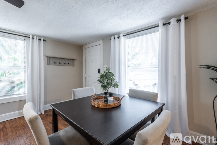 A dining room with a black table and white chairs.