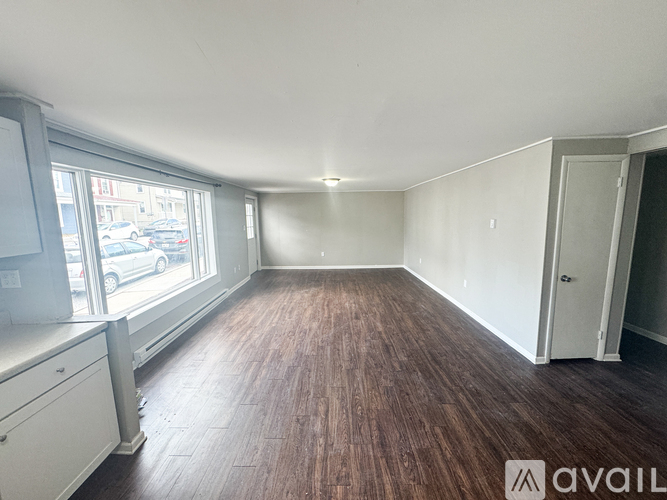 A room with wooden flooring and a window overlooking a street.