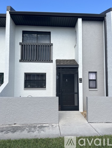 A modern two-story house with a black front door and a balcony on the second floor.