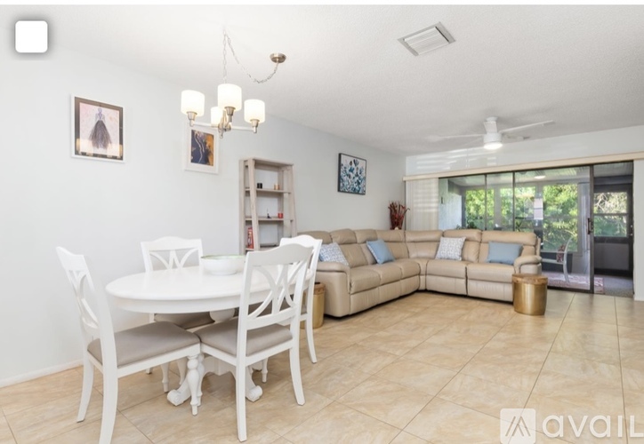 A living room with a white dining table and chairs, a beige sofa, and a chandelier.