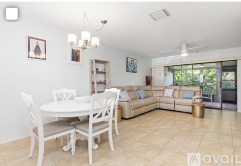 A living room with a white dining table and chairs, a beige sofa, and a chandelier.