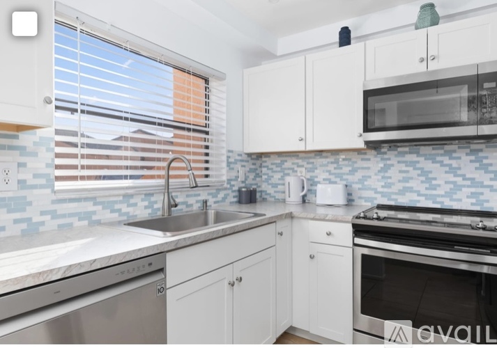 A kitchen with white cabinets and a blue tile backsplash.