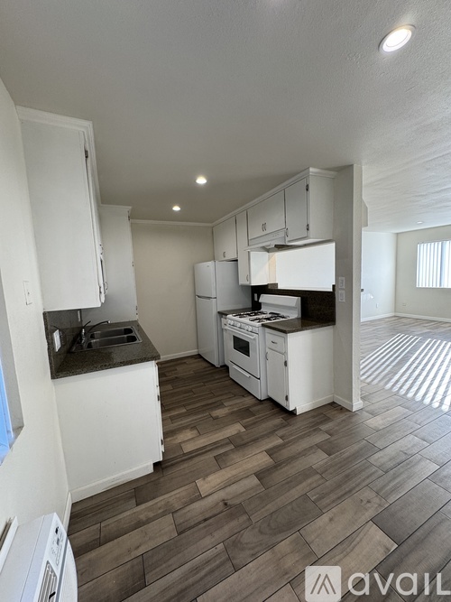 A kitchen with white cabinets and a wooden floor.