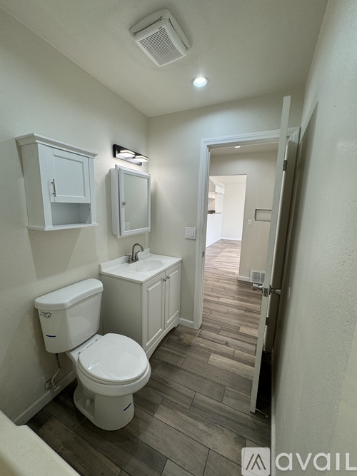A bathroom with a toilet, sink, and cabinet.