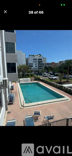 A pool surrounded by chairs and buildings.