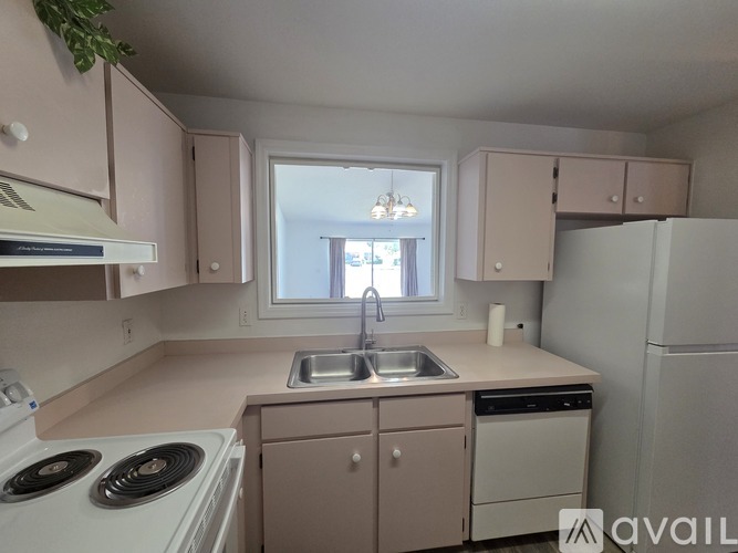 A kitchen with a white stove top oven, a white sink, and a white refrigerator.