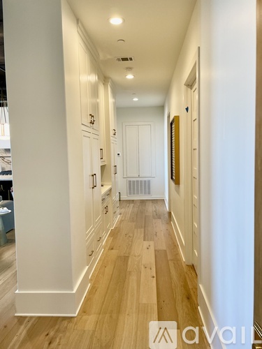 A long hallway with wood floors and white walls.