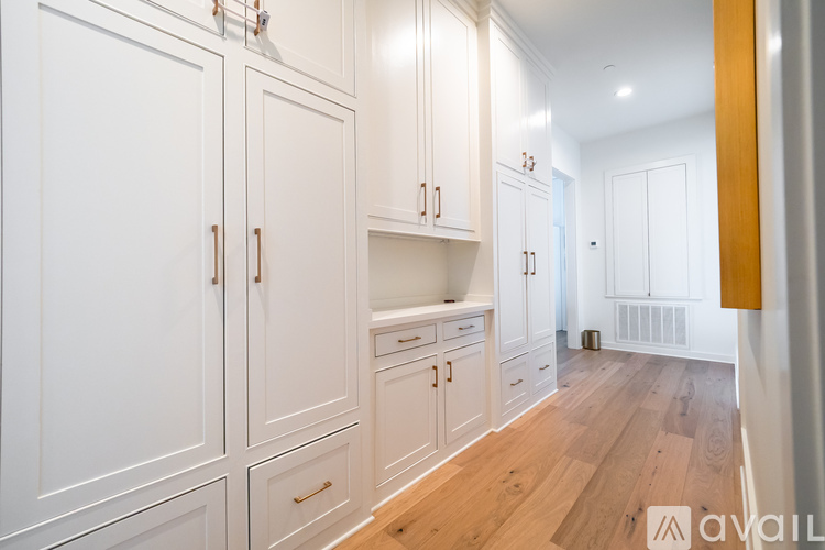 A kitchen with white cabinets and wooden floors.