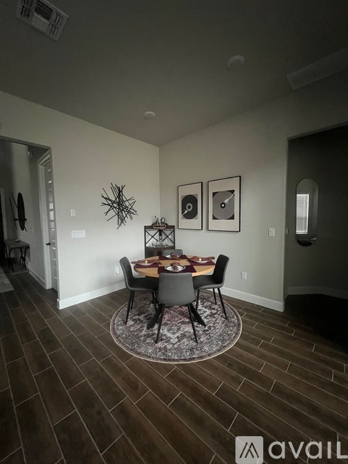 A dining room with a table set for two and a rug on the floor.