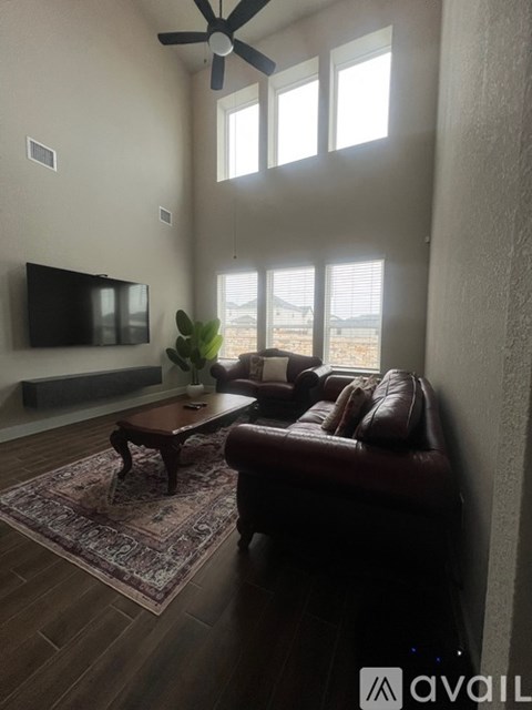 A living room with a brown leather couch and a rug.