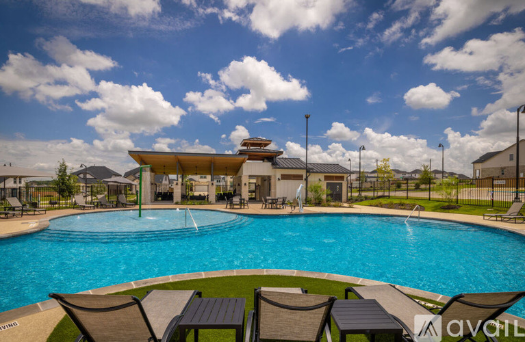 A pool with chairs around it and a building in the background.