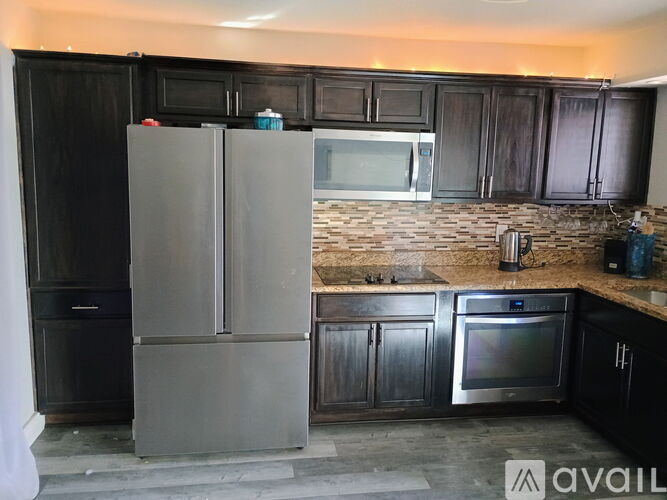 A kitchen with black cabinets and a silver refrigerator.
