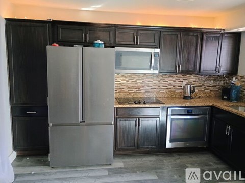 A kitchen with black cabinets and a silver refrigerator.