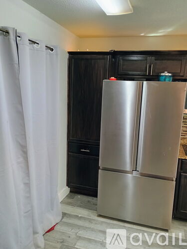 A stainless steel refrigerator in a kitchen with black cabinets.