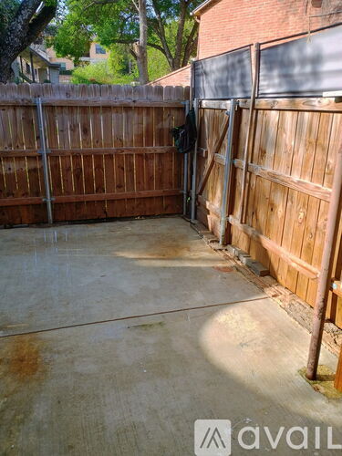 A wooden fence encloses a concrete patio.