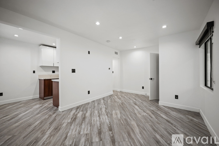 A spacious room with wood flooring and white walls.