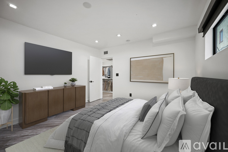 A modern bedroom with a large bed and a flat screen TV mounted on the wall.