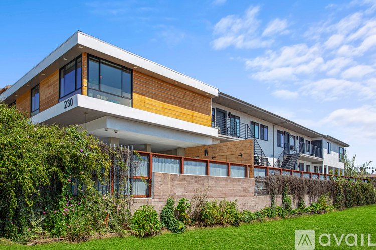 A modern house with a white and wood exterior and a green lawn in front.