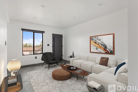 A living room with a white couch, a black chair, and a painting on the wall.