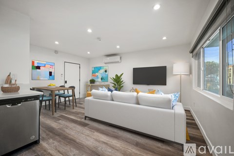 A modern living room with a white sofa and a wooden dining table.