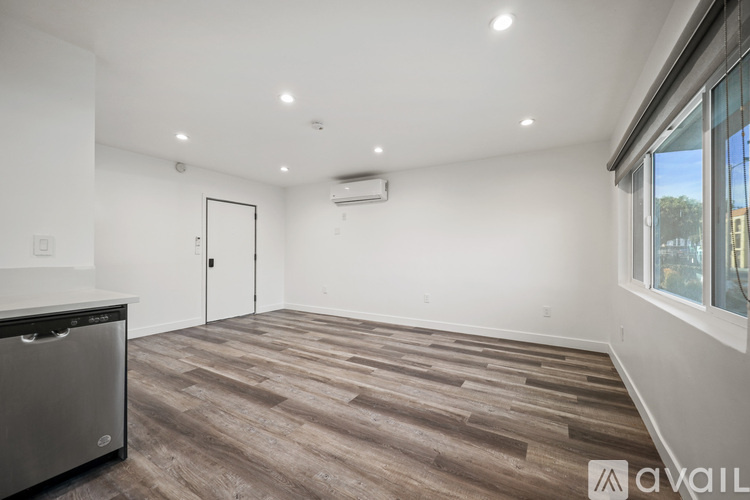 A spacious room with wooden flooring and a large window.