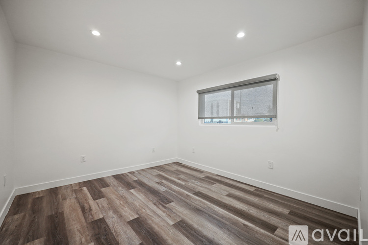 A room with wooden flooring and a window showing a view of a building.