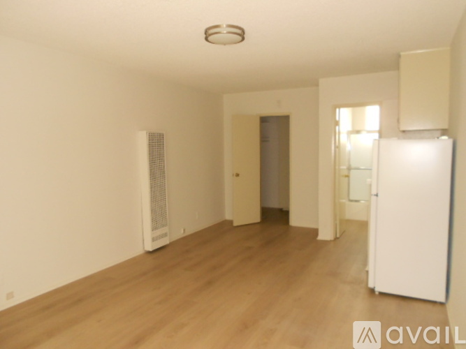 A spacious room with wooden flooring and white walls.