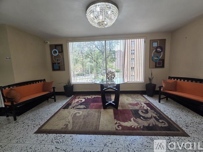 A living room with a rug, two sofas, and a chandelier.