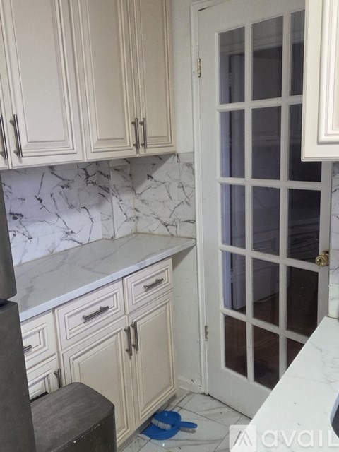 A kitchen with white cabinets and a marble countertop.
