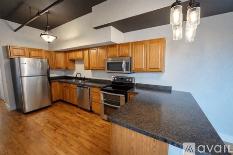 A kitchen with wooden cabinets and a stainless steel refrigerator.