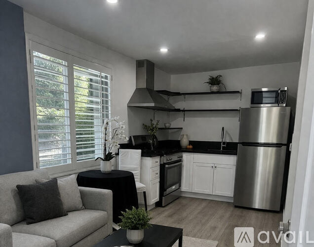 A modern kitchen with a grey couch and a black table.