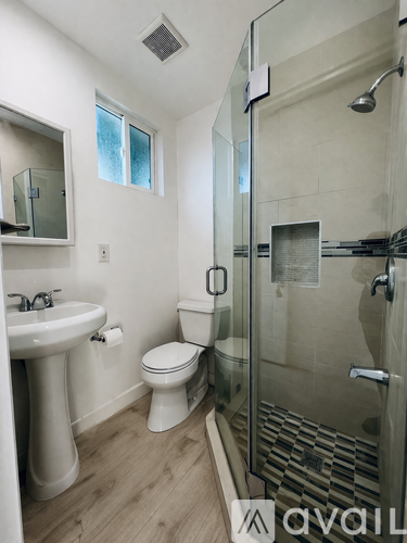 A bathroom with a toilet, sink, and shower.