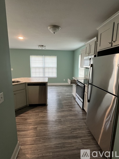 A kitchen with a stainless steel refrigerator and wooden flooring.