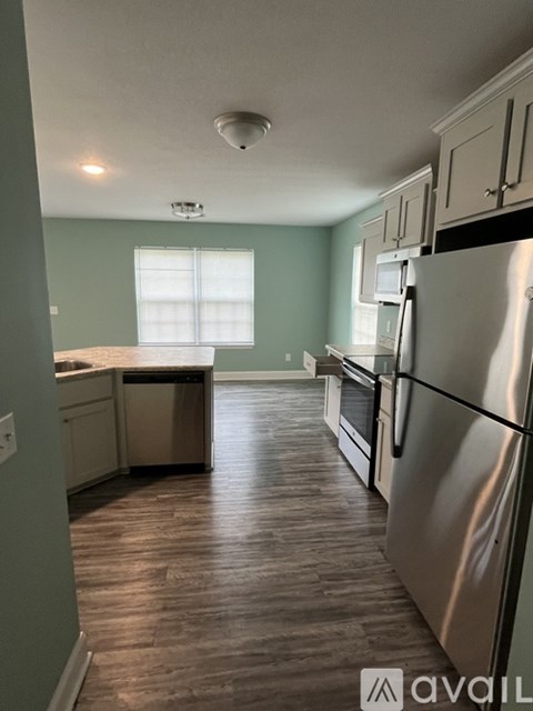 A kitchen with a stainless steel refrigerator and wooden flooring.