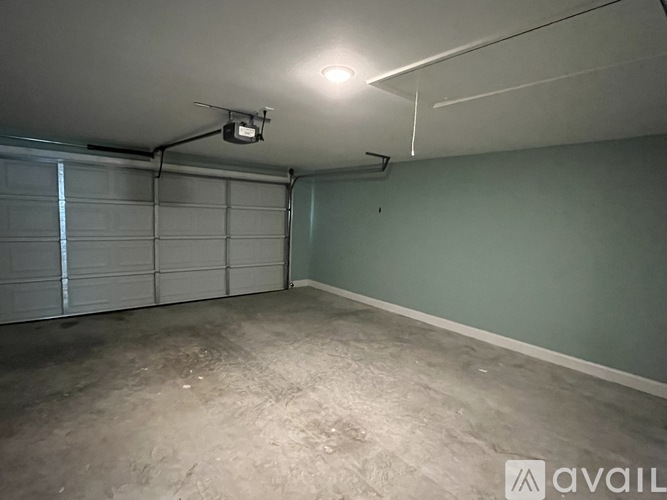 A spacious garage with a closed white door and a light on the ceiling.