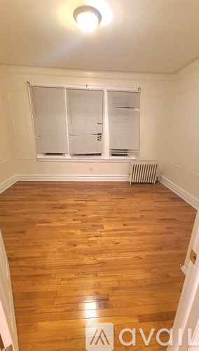 A room with wooden floors and a window with blinds.