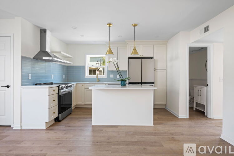 A kitchen with a white island and a stainless steel refrigerator.
