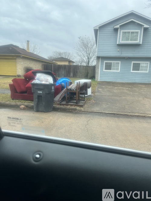 A blue house with a red couch and a black trash can in front of it.