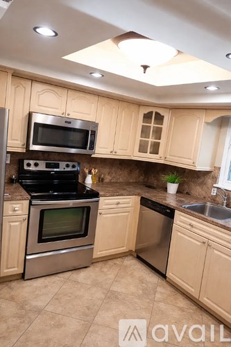 A kitchen with beige cabinets and stainless steel appliances.