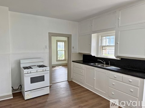 A kitchen with white cabinets and a black countertop.