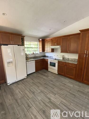 A kitchen with white appliances and wooden cabinets.