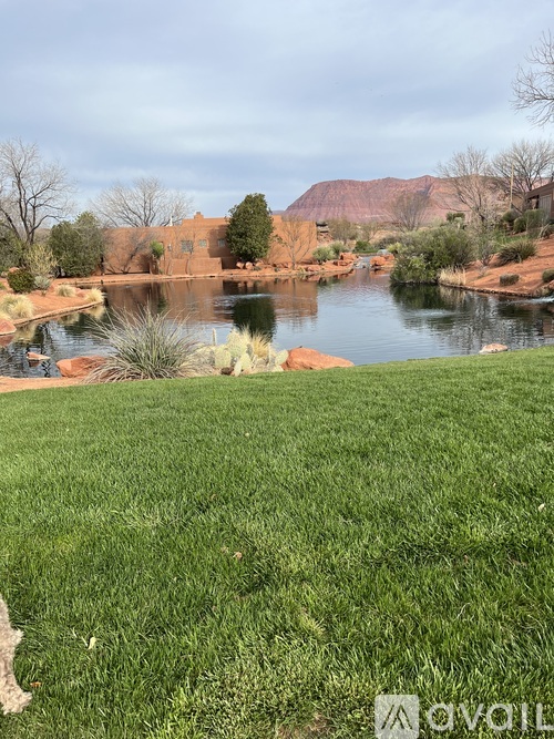 A grassy area in front of a body of water with a building in the background.