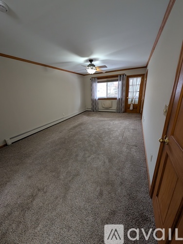 A carpeted room with a window and a door.