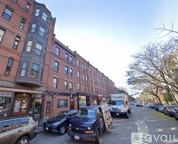 A street view of a row of buildings with cars parked on the side.