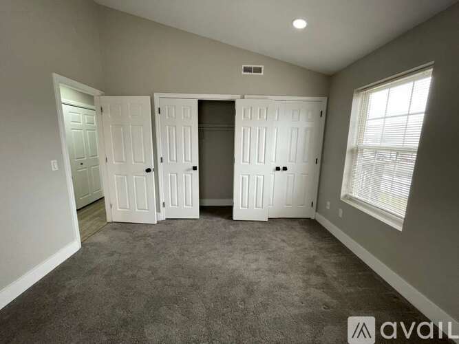 A room with a carpeted floor and a window with blinds.