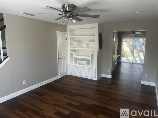 A room with a ceiling fan and wooden flooring.