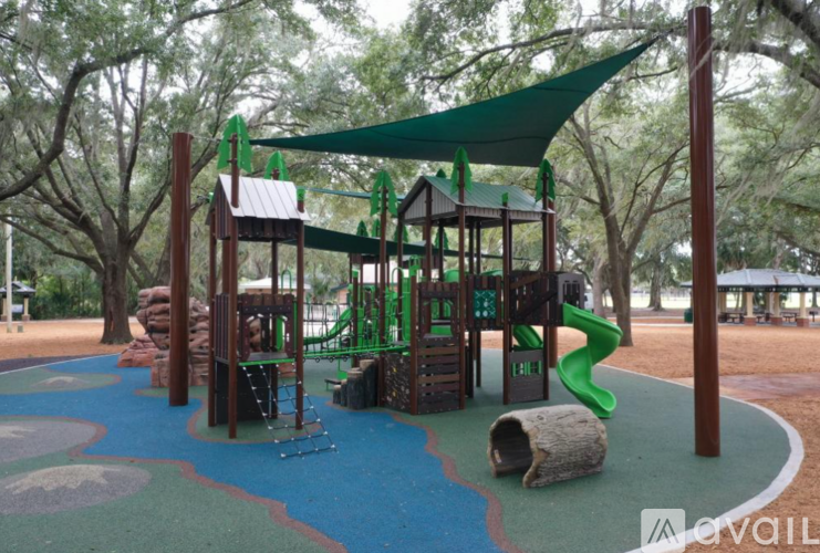A playground with a green slide and a brown wooden structure.