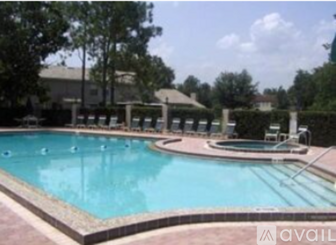 A large outdoor swimming pool surrounded by trees and a pavilion.
