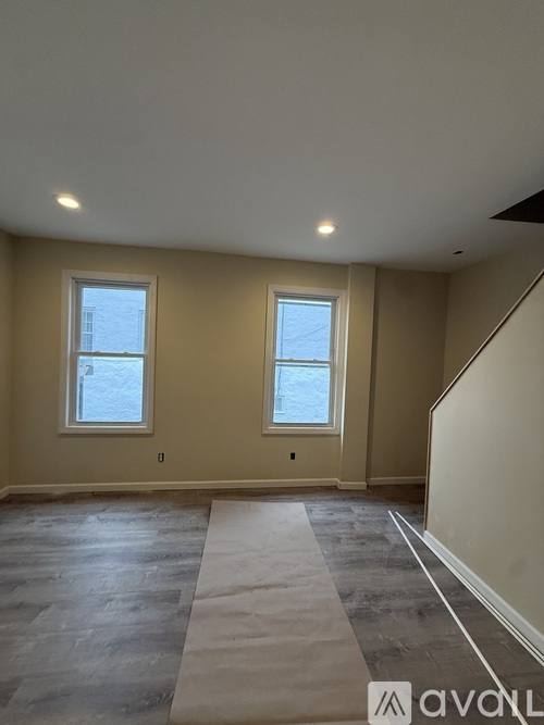 A room with two windows and a grey carpet.
