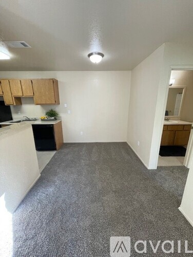 A room with a grey carpet and wooden cabinets.